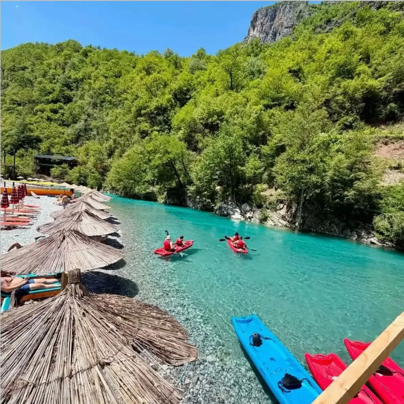 Kayaks and shaded sunbeds beside the river